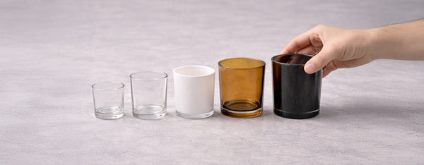 Five candle glasses in a row from small clear to white, amber and black