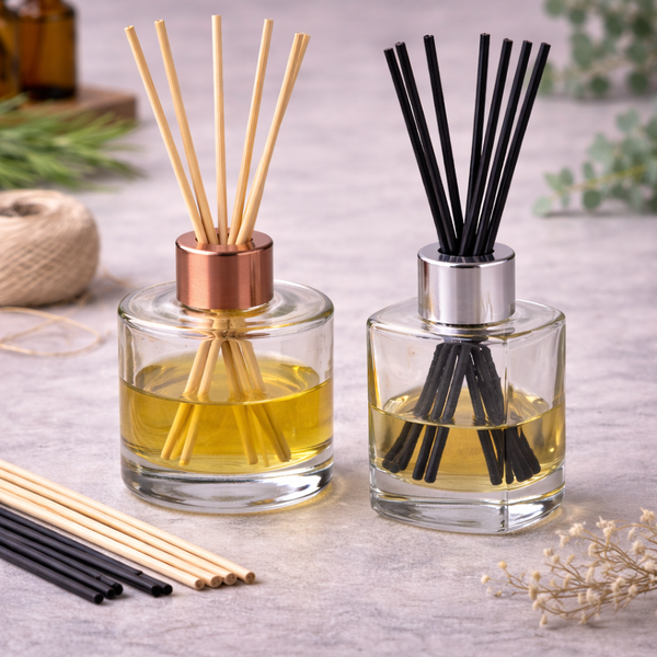 Two reed diffusers, one with a copper cap and natural reeds, one with a silver cap and black fibre reeds