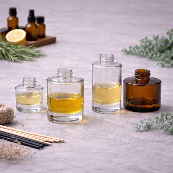 Four diffuser bottles in different sizes and shapes, three clear and one amber, filled with fragrance oil